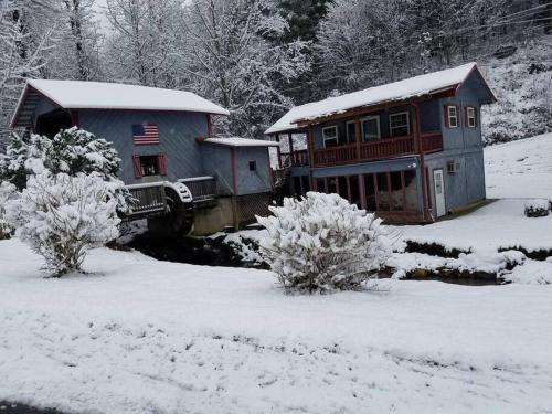 a house in the snow next to a building at Waterwheel Cabin by the Creek in Murphy