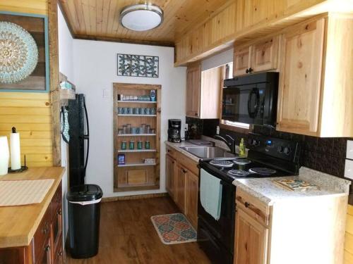 a kitchen with wooden cabinets and a black stove top oven at Waterwheel Cabin by the Creek in Murphy