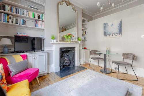- un salon avec une cheminée et une table dans l'établissement Vogue 1 bedroom Pimlico flat near Victoria Station, à Londres