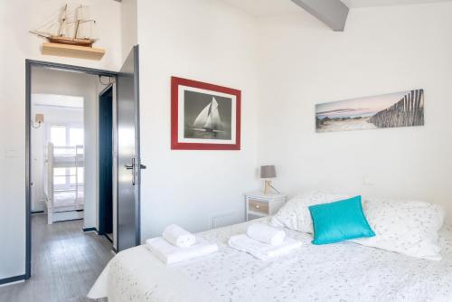 a bedroom with a white bed with a blue pillow at Appartement Valène in La Flotte
