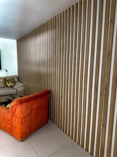 a room with a wooden wall with an orange couch at Cabaña en santafe de Antioquia in Santa Fe de Antioquia