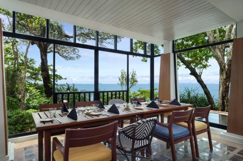 een eetkamer met een tafel en stoelen en grote ramen bij Avani Plus Koh Lanta Krabi Resort in Koh Lanta