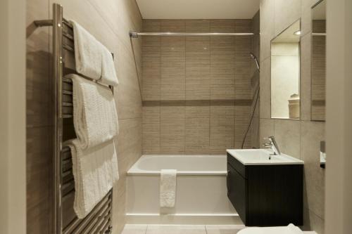 een badkamer met een bad en een wastafel bij The Harlesden Escape - Spacious 3BDR Flat with Balcony in Londen