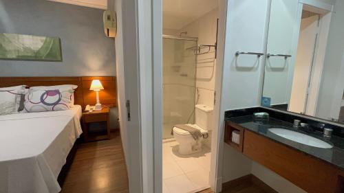 y baño con cama, ducha y lavabo. en Flat 2 Quartos - Rua Alvorada 1009 en São Paulo