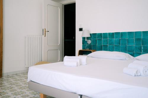 a large white bed in a room with blue tiles at Casa Flora in Vietri sul Mare