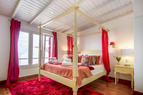 a bedroom with a canopy bed with red curtains at Villa de la Plage in Albufeira