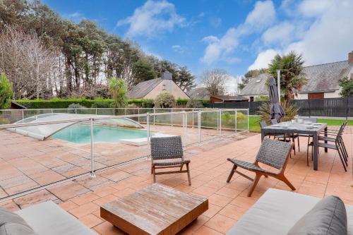 un patio avec une table et des chaises et une piscine dans l'établissement Plages piscine et détente à Arzon, à Arzon
