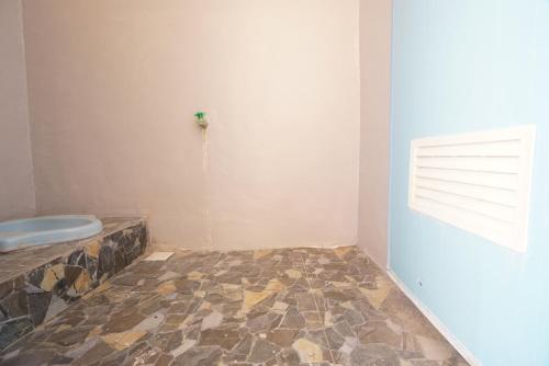 La salle de bains est pourvue de toilettes et d'un mur avec une fenêtre. dans l'établissement SPOT ON 93685 Homestay Bu Sun Syariah, à Sidoarjo