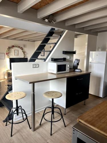 une cuisine avec un comptoir, un four micro-ondes et des tabourets dans l'établissement L'Éden - Centre ville & Gare, à Rennes