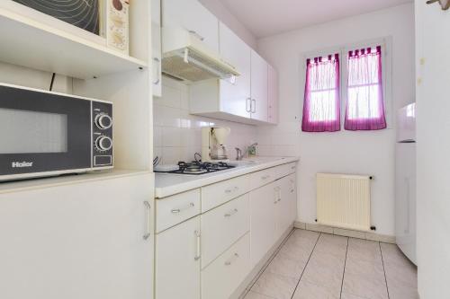 une cuisine avec des armoires blanches et un micro-ondes dans l'établissement Escapade tout près du Port et de la plage, à Saint-Gilles-Croix-de-Vie