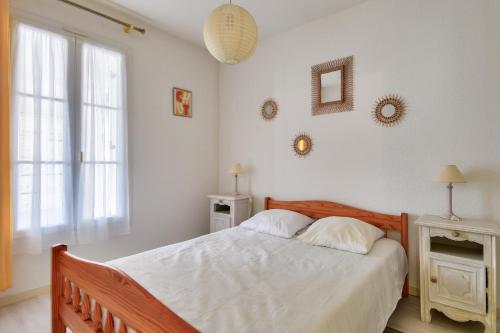 une chambre avec un lit avec des draps blancs et une fenêtre dans l'établissement Escapade tout près du Port et de la plage, à Saint-Gilles-Croix-de-Vie