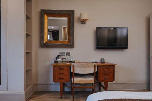 a hotel room with a desk with a mirror and a tv at Rose and Crown Stoke Newington in London