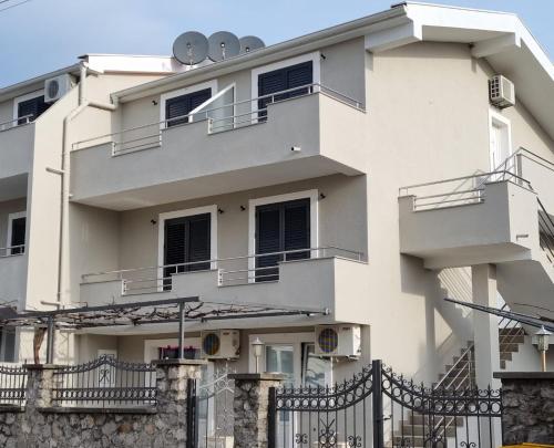 a white building with balconies and a fence at Apartments Ljubica Tivat in Tivat