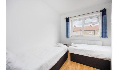 two beds in a room with a window at Shortlet Express, Large 4 bedroom house, 2 baths in East Ham in London