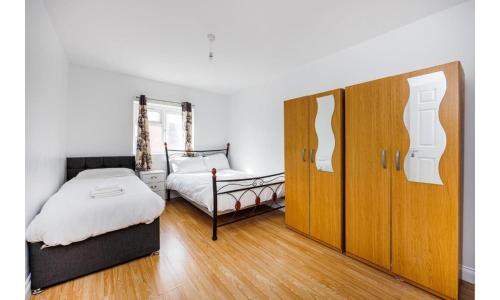 a bedroom with a bed and a dresser and a bed and a cabinet at Shortlet Express, Large 4 bedroom house, 2 baths in East Ham in London