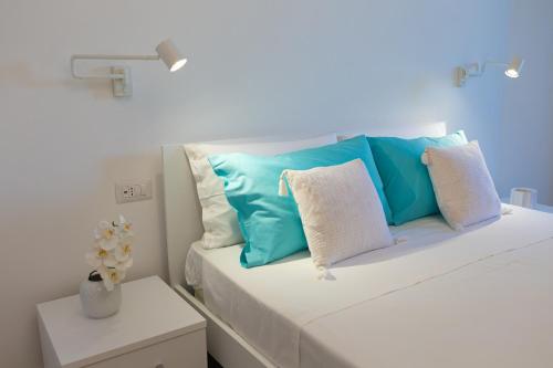 Una cama blanca con almohadas azules y blancas. en Estia Suites en Villasimius