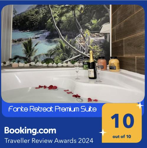 a bath tub with a bottle of wine and glasses at Fonte Retreat Premium Suite in Sandim