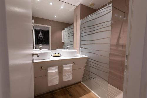a bathroom with two sinks and a shower at Grand Hôtel Du Tonneau D'Or in Belfort