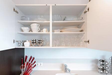 a kitchen with a sink and a white cabinet with dishes at Modern 2BR Apt in Sandweiler with Terrace in Sandweiler