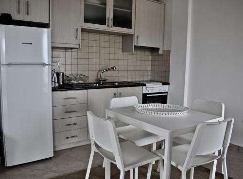 una cucina con tavolo, sedie e frigorifero bianco di Cycladic house on Agios Spyridonas beach a Andiparos