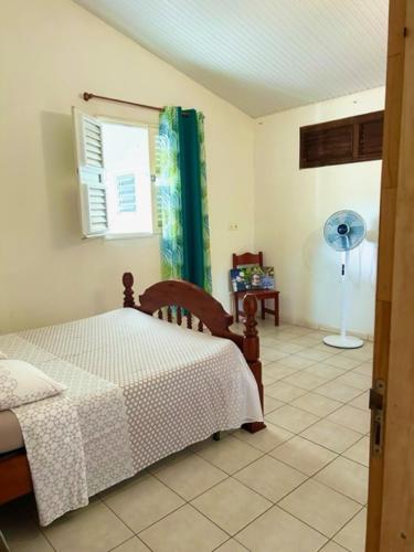 a bedroom with a bed and a window with a fan at Cloison du BONHEUR in Le Lamentin