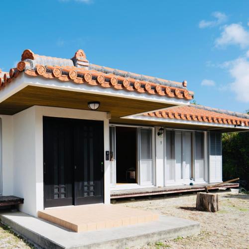 a small white house with a red roof at totono house 満天の星空 テントサウナ BBQ 元有形文化財を1棟貸切 うるま市 浜比嘉島 in Uruma