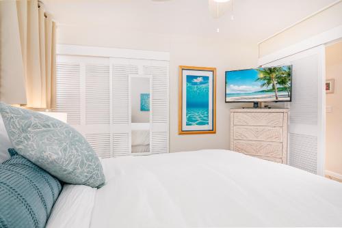 a white bedroom with a bed and a television at ***SERENDIPITY ON THE MOANA - Legal & Oceanfront - Great for Work & Play!*** in Waianae