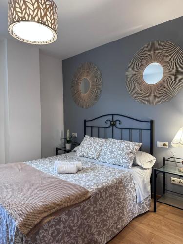 a bedroom with a bed with two mirrors on the wall at Apartamento La Emisora in Ponferrada