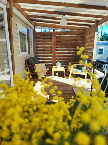 une véranda avec une table et des fleurs jaunes dans l'établissement Mobil home les dunes de contis 