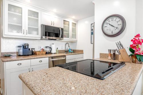 a kitchen with a counter with a clock on the wall at ***SERENDIPITY ON THE MOANA - Legal & Oceanfront - Great for Work & Play!*** in Waianae