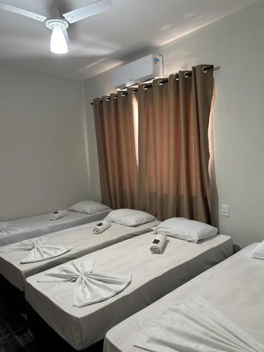 three beds in a room with a curtain at Pousada Recanto Da Fé in Aparecida