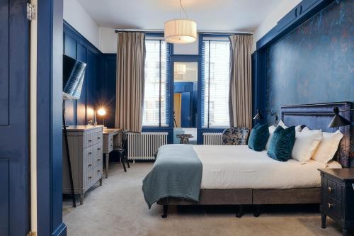 um quarto com paredes azuis, uma cama e uma secretária em Rose and Crown Stoke Newington em Londres