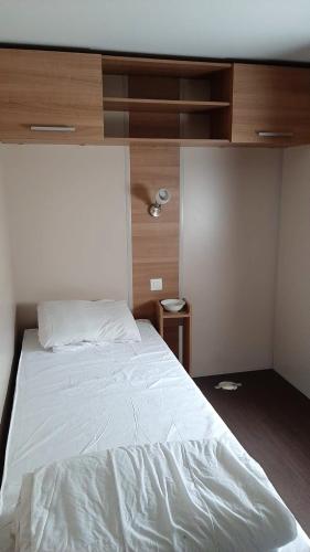 - une chambre avec un lit blanc et un mur en bois dans l'établissement Bungalow à Onzain avec piscine partagée et jardin, à Onzain