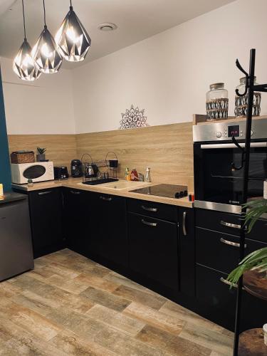 - une cuisine avec des placards noirs et un évier dans l'établissement Love room - love&cocon, à Fontenille-Saint-Martin-d'Entraigues