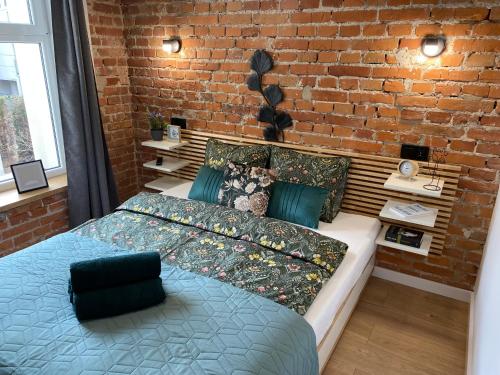 a bedroom with a bed with a brick wall at Konarskiego Residence in Kraków