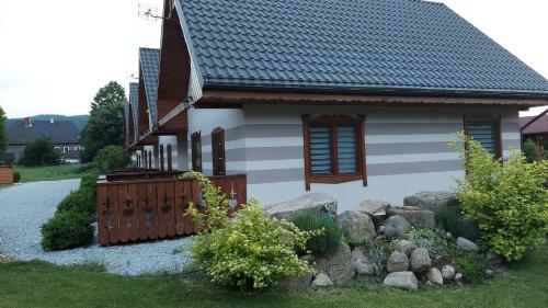 a white house with a fence and some rocks at Domki u Justyny Podgórzyn Karpacz Sosnówka in Podgórzyn