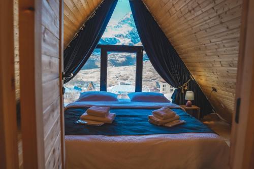RestArt Cottages in Kazbegi في كازباجي: غرفة نوم بسرير مطل على جبل