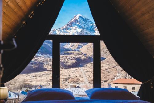 a view of a snow covered mountain from a window at RestArt Cottages in Kazbegi in Stepantsminda