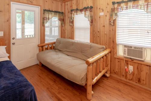 una camera da letto con divano in una stanza con pareti in legno di Jellystone Park at Natural Bridge 