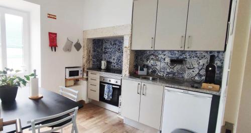 a kitchen with white cabinets and a table in a room at Casa do Albuquerque II in Sintra