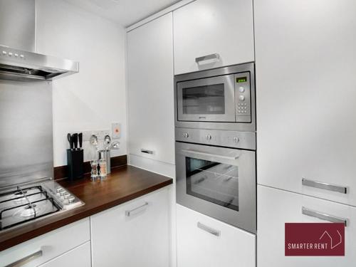 a kitchen with a stove and a microwave at Bracknell - 2 Bedroom House With Garden in Bracknell
