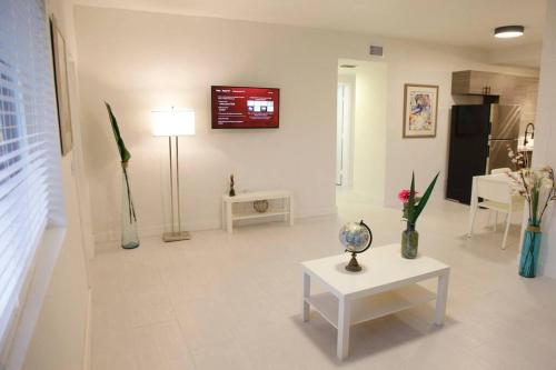 uma sala de estar com uma mesa e uma televisão na parede em Apt 2 Miami Designer Apartment in the Upper East-Side em Miami