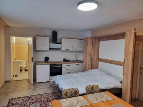 a small bedroom with a bed and a kitchen at Apartamenty Łąkowa Piecki in Piecki
