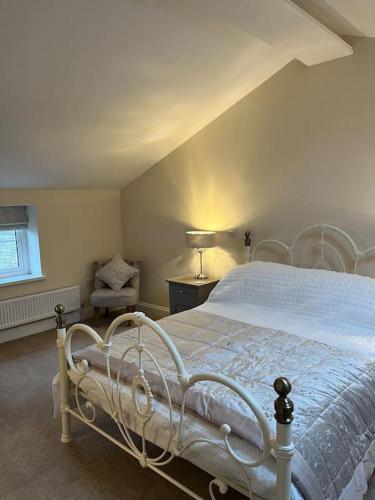 a bedroom with a white bed and a chair at Converted Barn with Hot Tub, The Hayloft. in Over Kellet