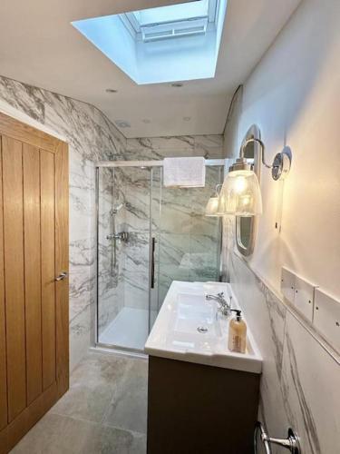 a bathroom with a shower and a sink and a mirror at Converted Barn with Hot Tub, The Hayloft. in Over Kellet