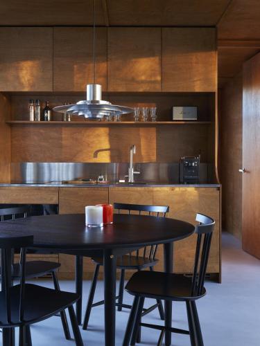 a kitchen with a table and chairs and a sink at Landet, Designer Cabins in the Swedish Archipelago in Västerljung