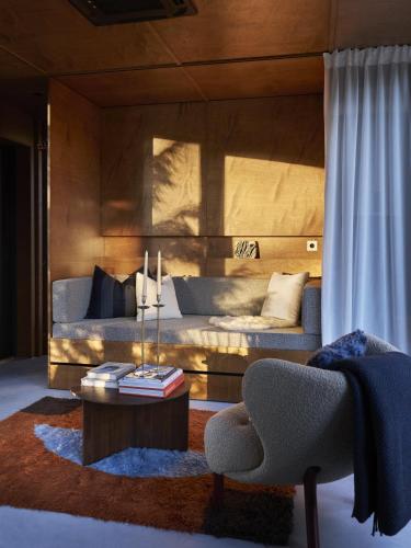 a living room with a couch and a table at Landet, Designer Cabins in the Swedish Archipelago in Västerljung