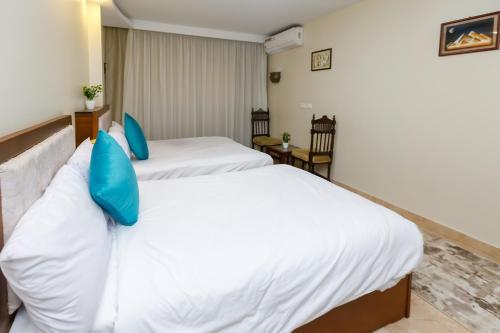 two beds in a hotel room with blue pillows at Diamond Pyramids View Inn in Cairo