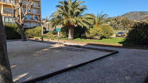 a parking lot with palm trees and a building at studio avec coin nuit, 100 m de la mer in Le Lavandou