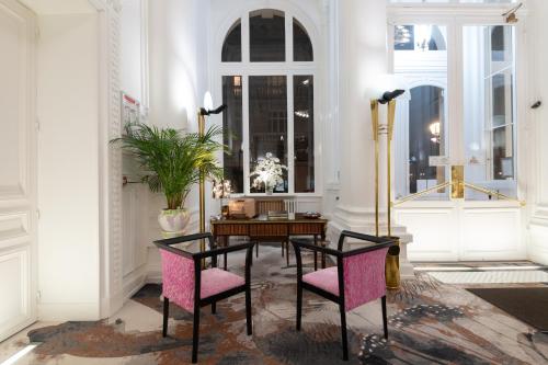 une chambre avec une table et deux chaises roses dans l'établissement Grand Hôtel Du Tonneau D'Or, à Belfort